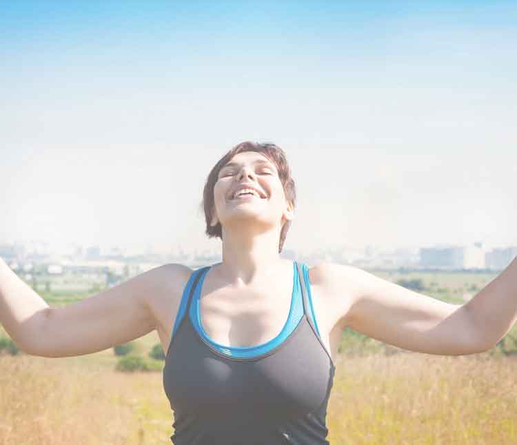 A woman with her arms outstretched in the middle of a field.