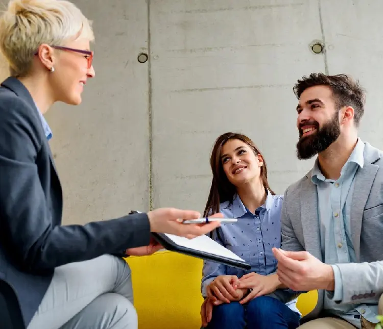 A woman is talking to two men in front of her.