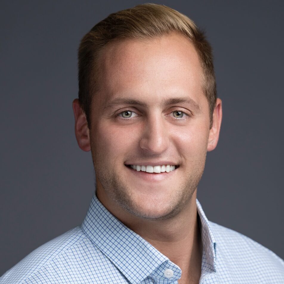 A man with blonde hair and blue shirt smiling.